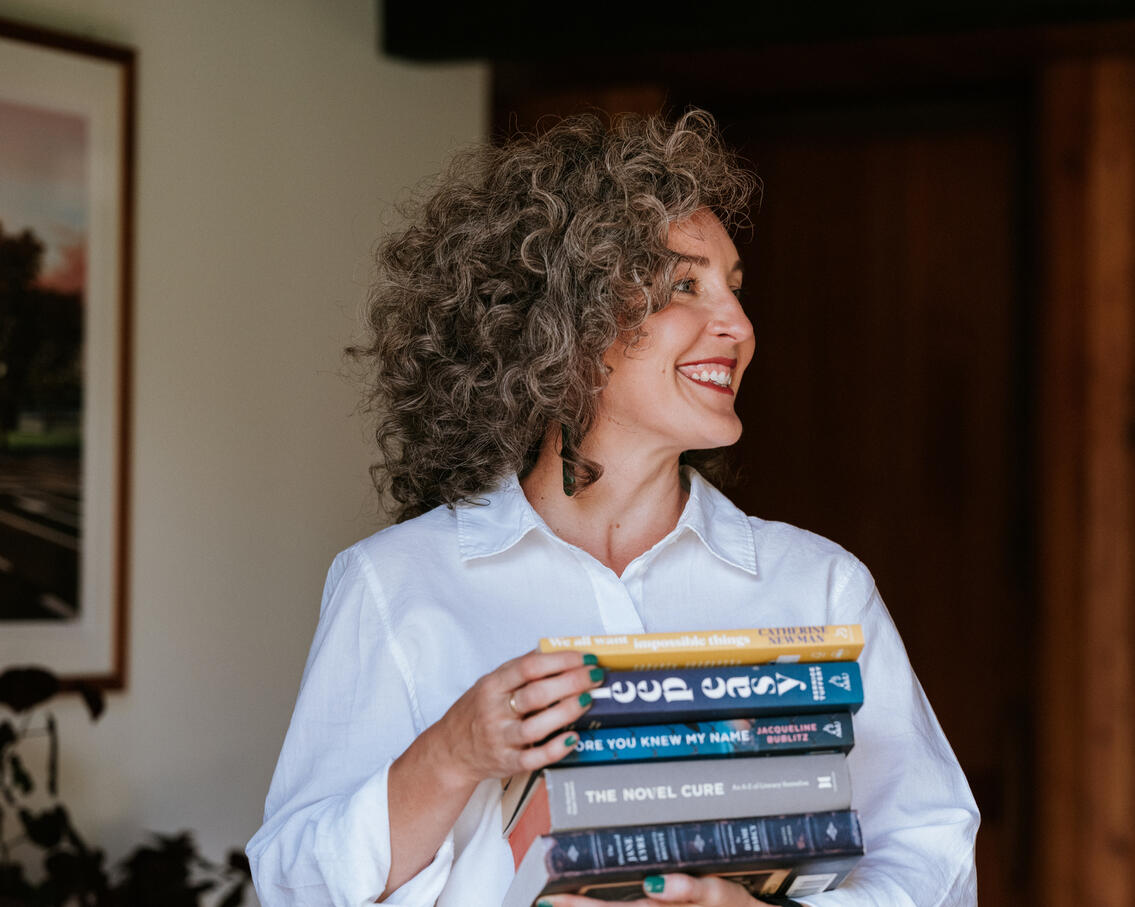 Professional branding photo of Kimberley Bartlett, registered counsellor and sleep therapist, photographed holding books as a symbol of learning and curiosity